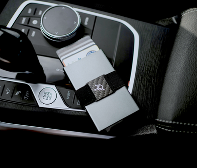 Carbon fiber modular wallet expansion pack placed on a car console, designed to increase card capacity without bulk.