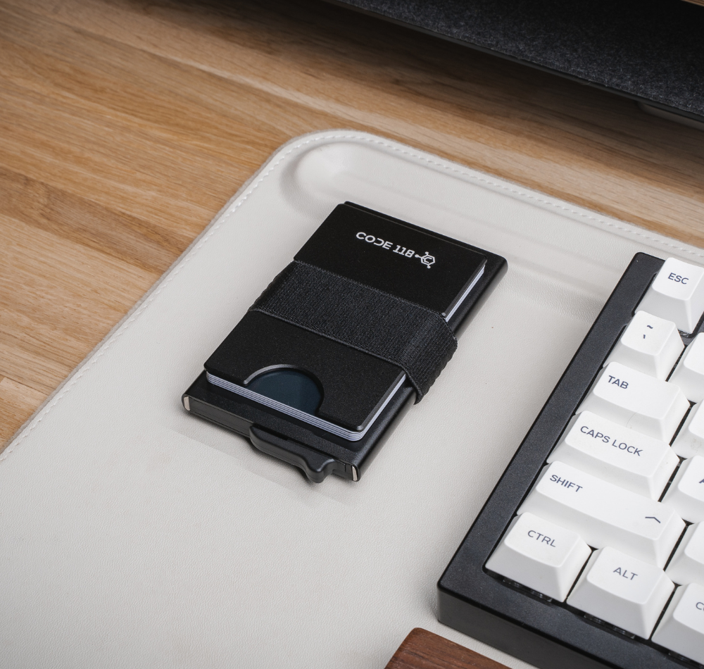 CODE 118 wallet with black Modular Backplate and extra cards on a desk beside a keyboard