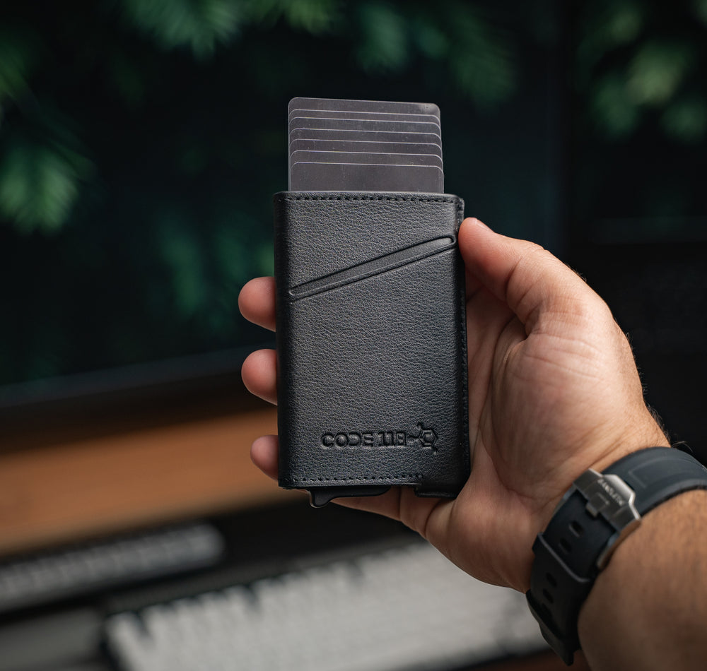 Hand holding a black CODE 118 Classic Leather Case with wallet cards fanned out at the top