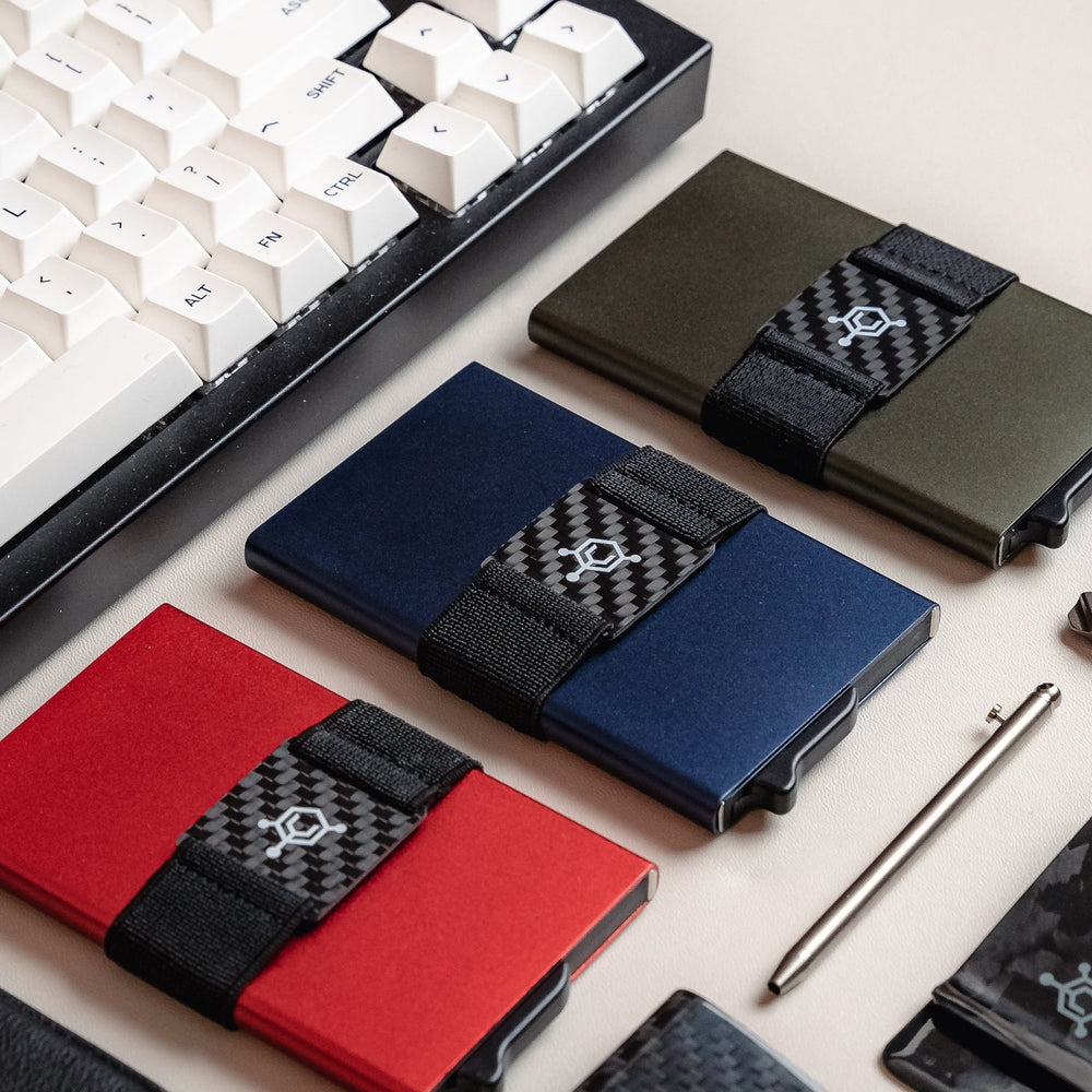 Three CODE 118 Wallets with carbon fiber cash straps on a desk